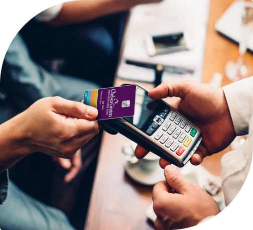 A man taps a purple Averon Trust visa debit card to a payment machine